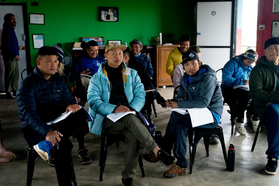 A group of adults sits in a circle of chairs in a community room, holding handouts.